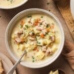 Two bowls filled with ham and potato soup with a spoon in one.