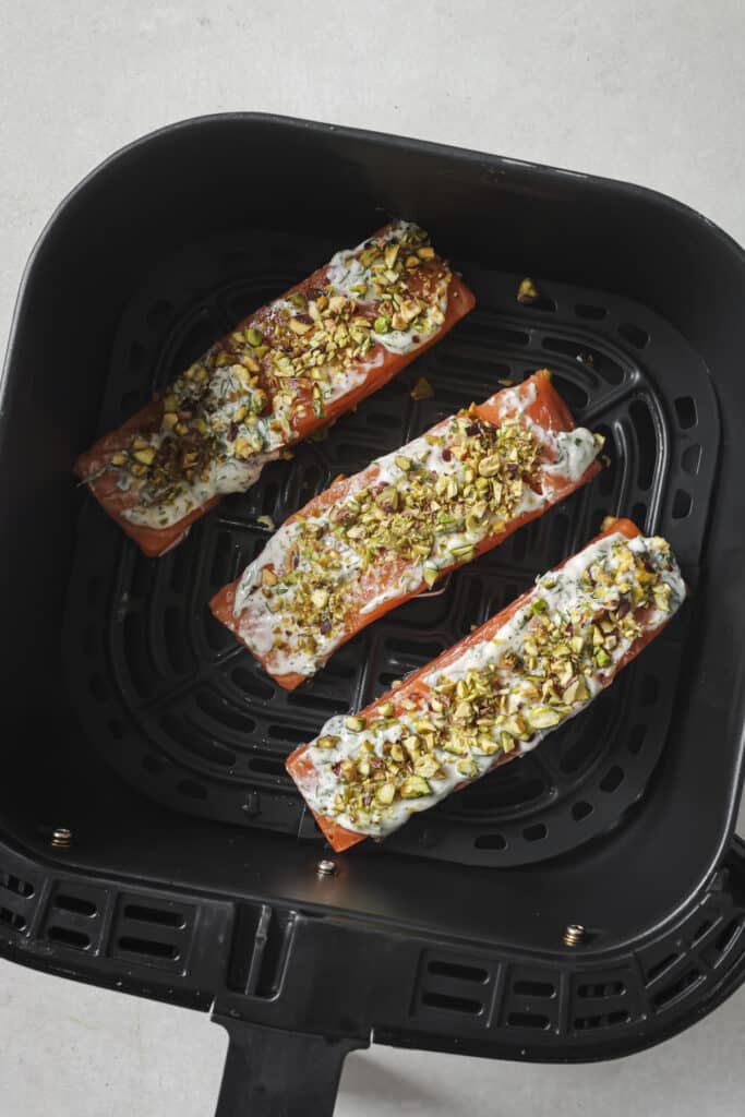 Uncooked salmon in an air fryer basket.