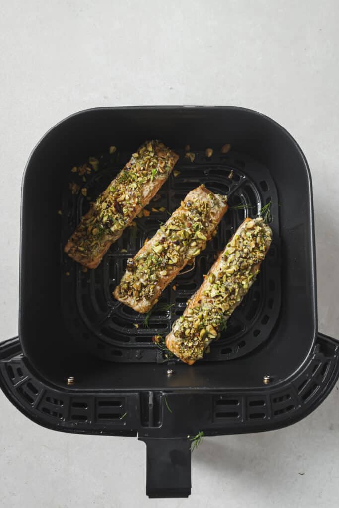 Pistachio crusted salmon in an air fryer basket.