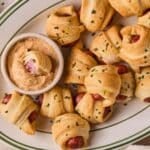 A plate full of air fryer pigs in a blanket with a side of homemade queso dip.