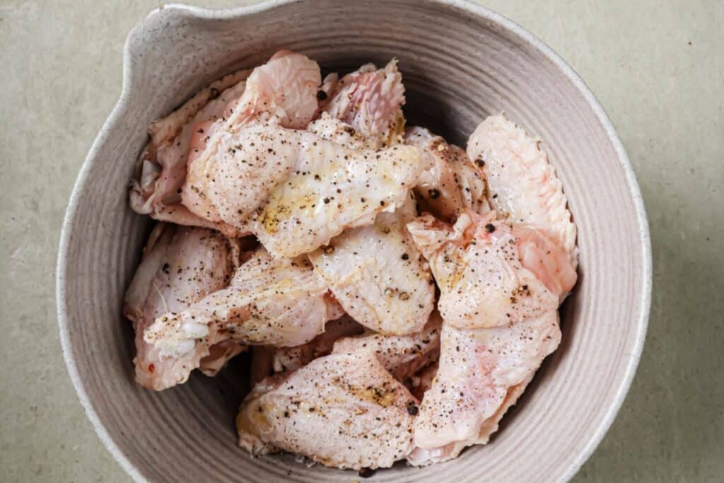 Seasoning chicken wings in a bowl.