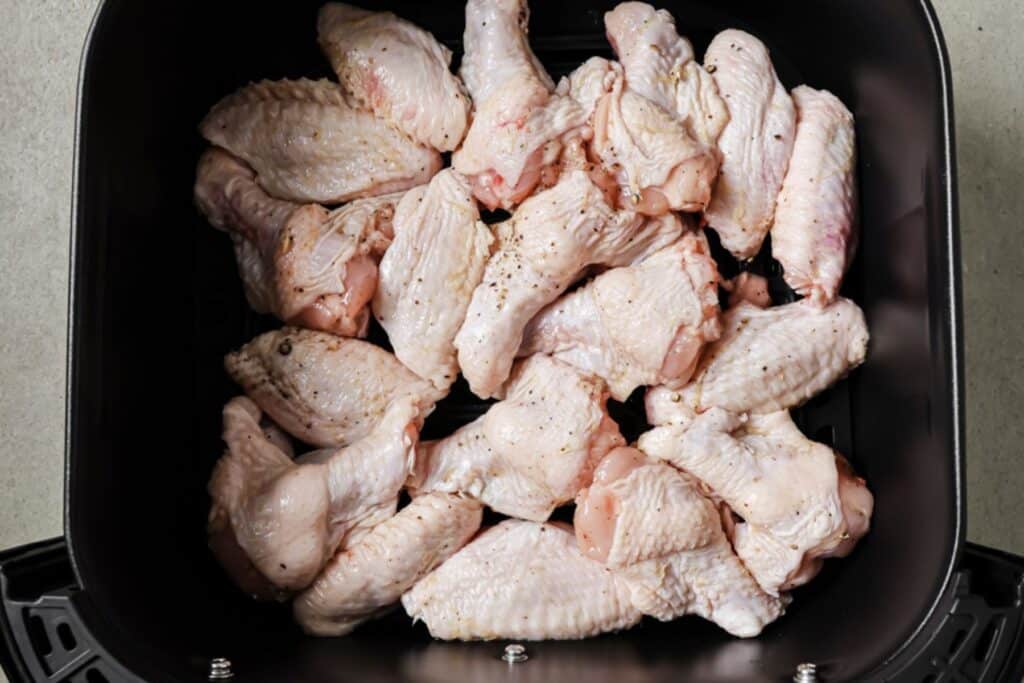 Chicken wings in the air fryer basket.