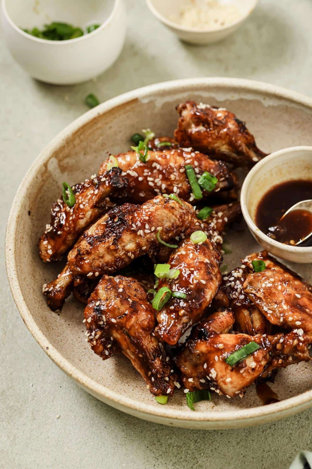 A plate of air fryer asian wings served with extra sauce.