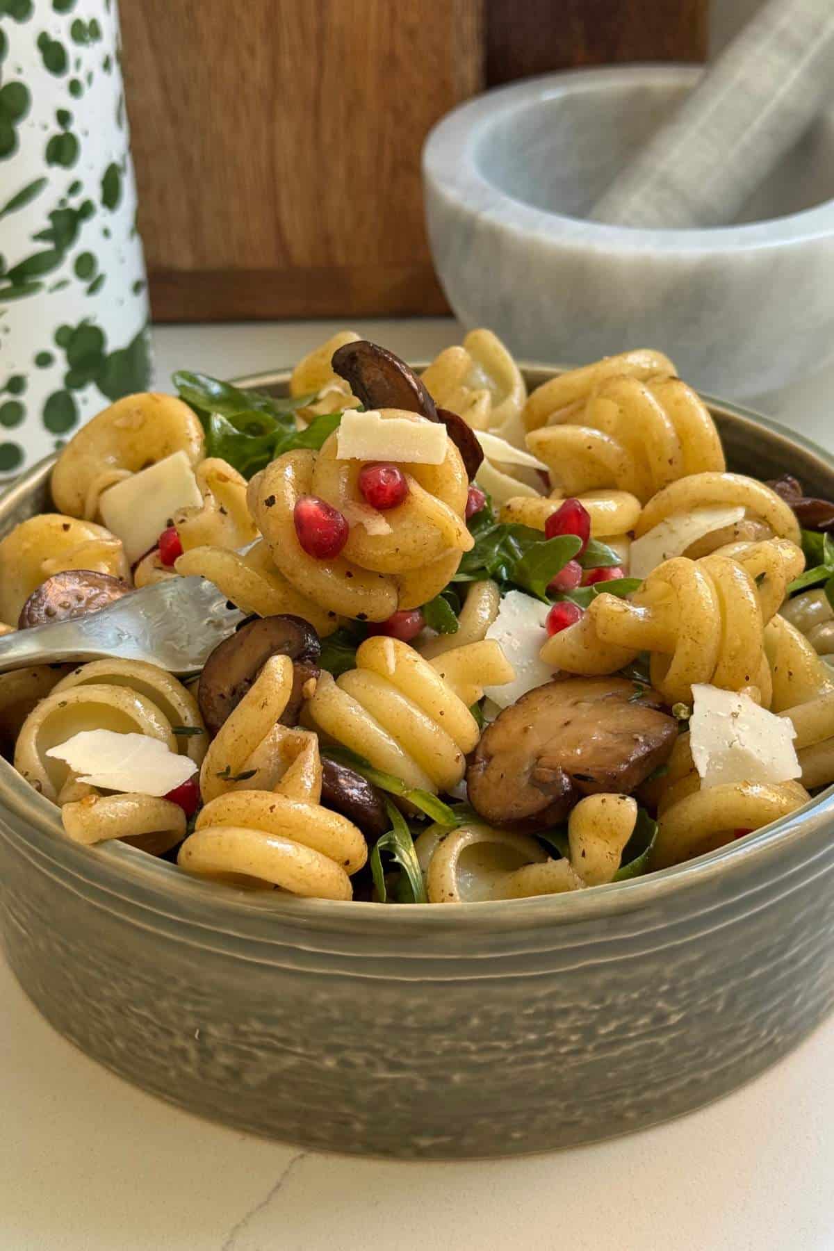 Mushroom pasta salad in a green bowl.