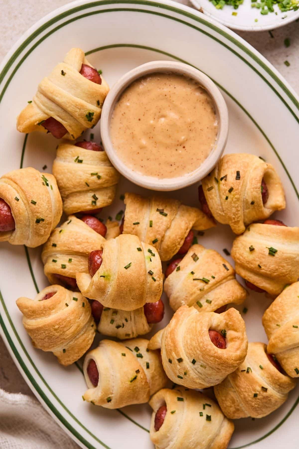 A plate of air fried pigs in a blanket with queso dip.
