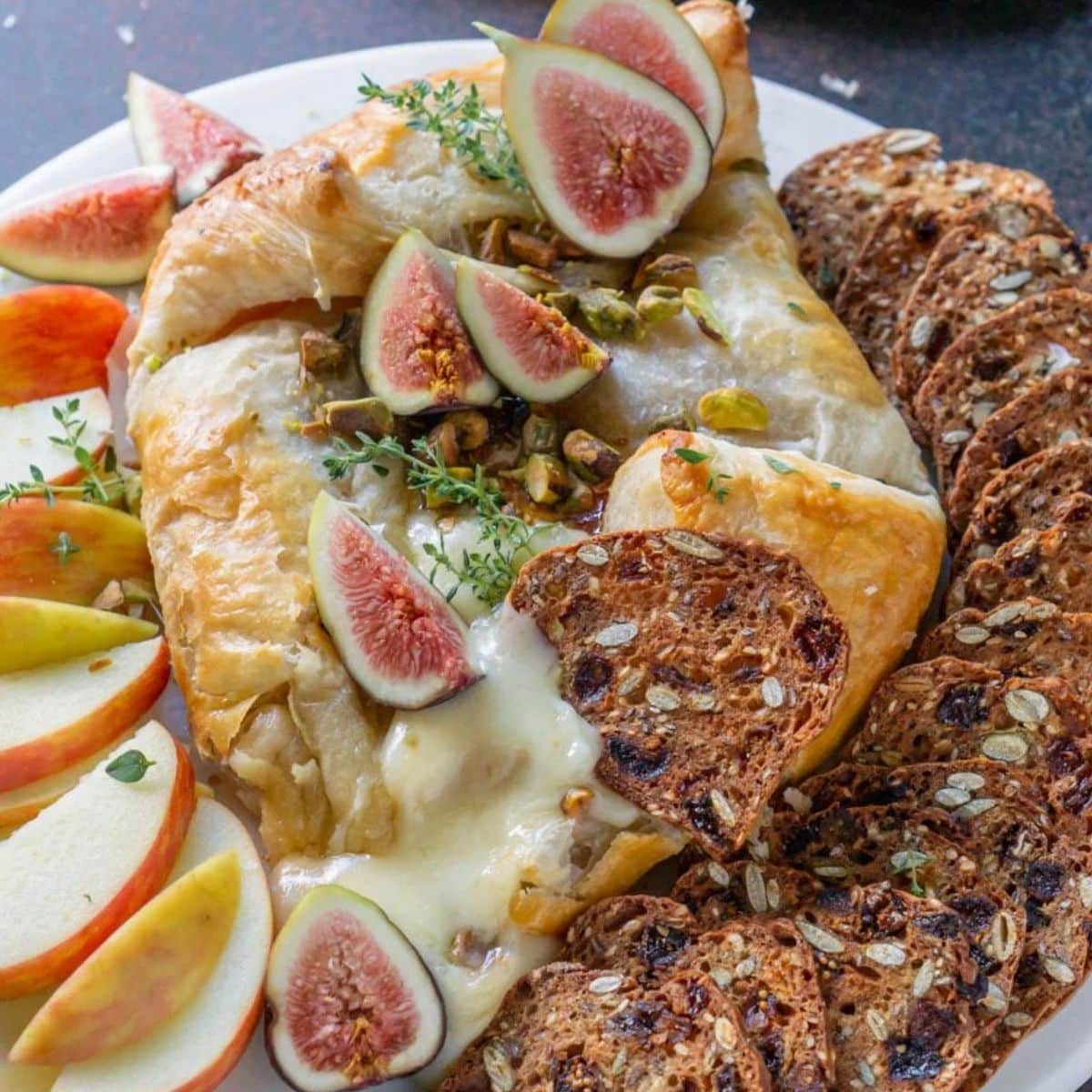 Baked brie topped with figs and served with crackers and apple slices.