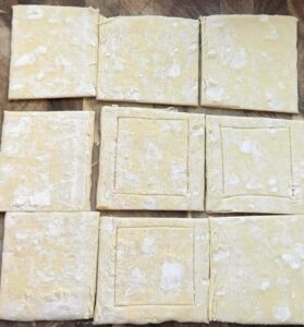 Puff pastry squares on a baking sheet pan.