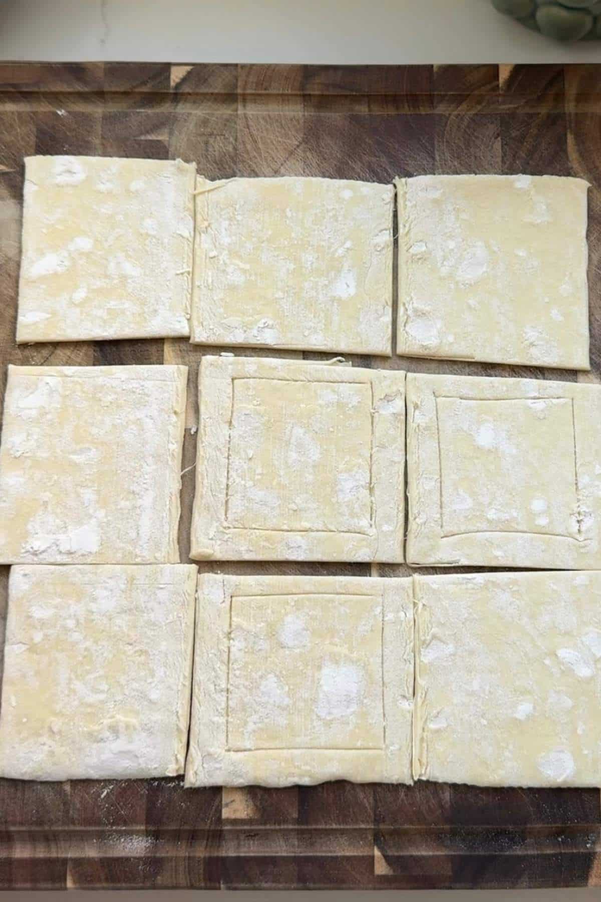 Puff pastry squares on a baking sheet pan.