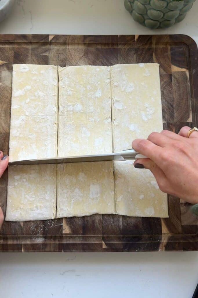 Cutting a sheet of puff pastry dough into squares.