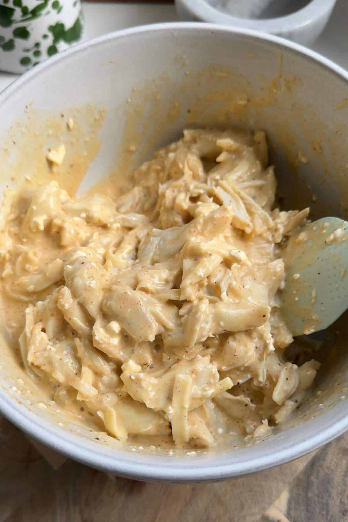 Stirring crab filling with a rubber spatula.