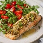Pistachio crusted salmon served alongside a green salad with tomatoes.