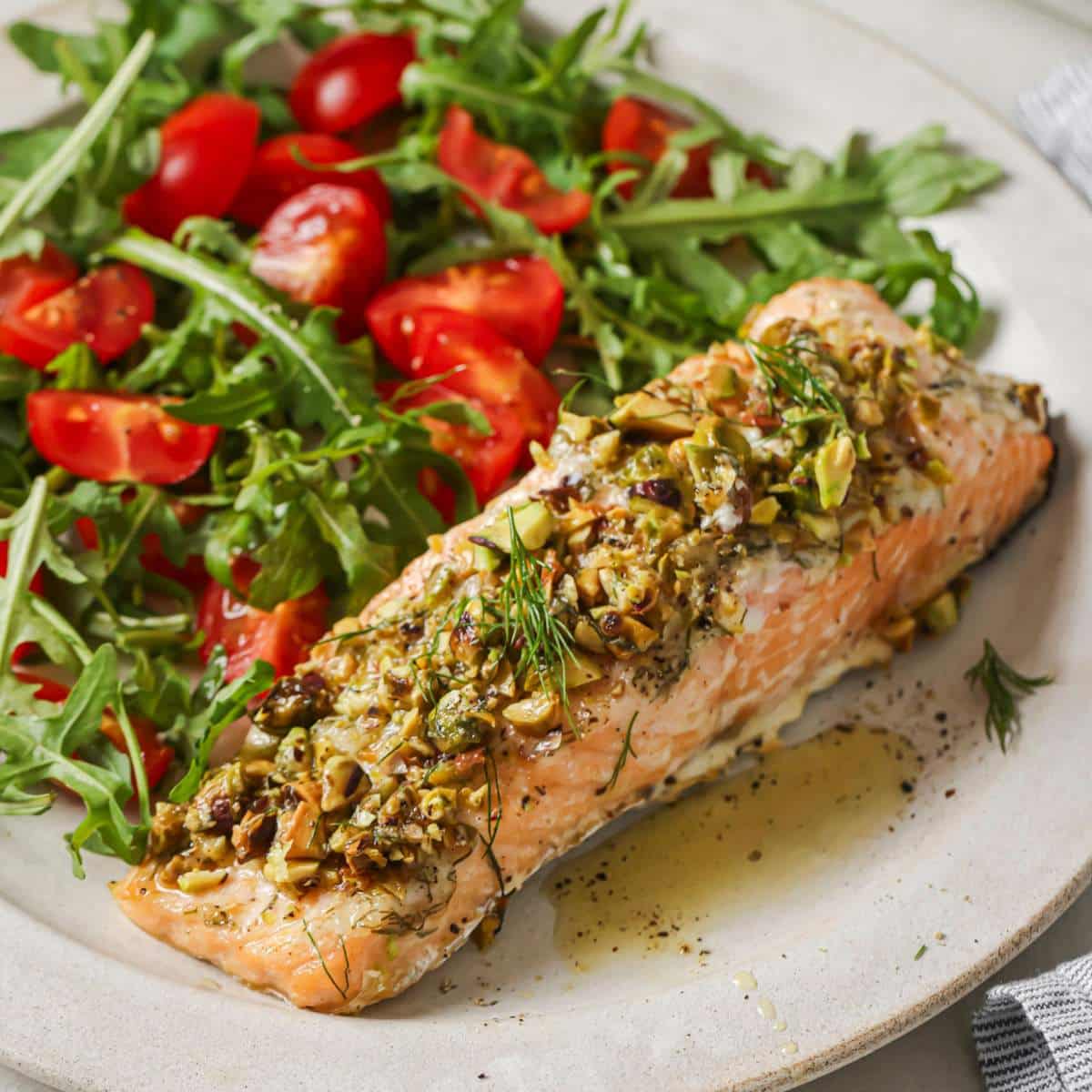 Pistachio crusted salmon served alongside a green salad with tomatoes.