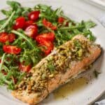 Pistachio crusted salmon served alongside a green salad with tomatoes.