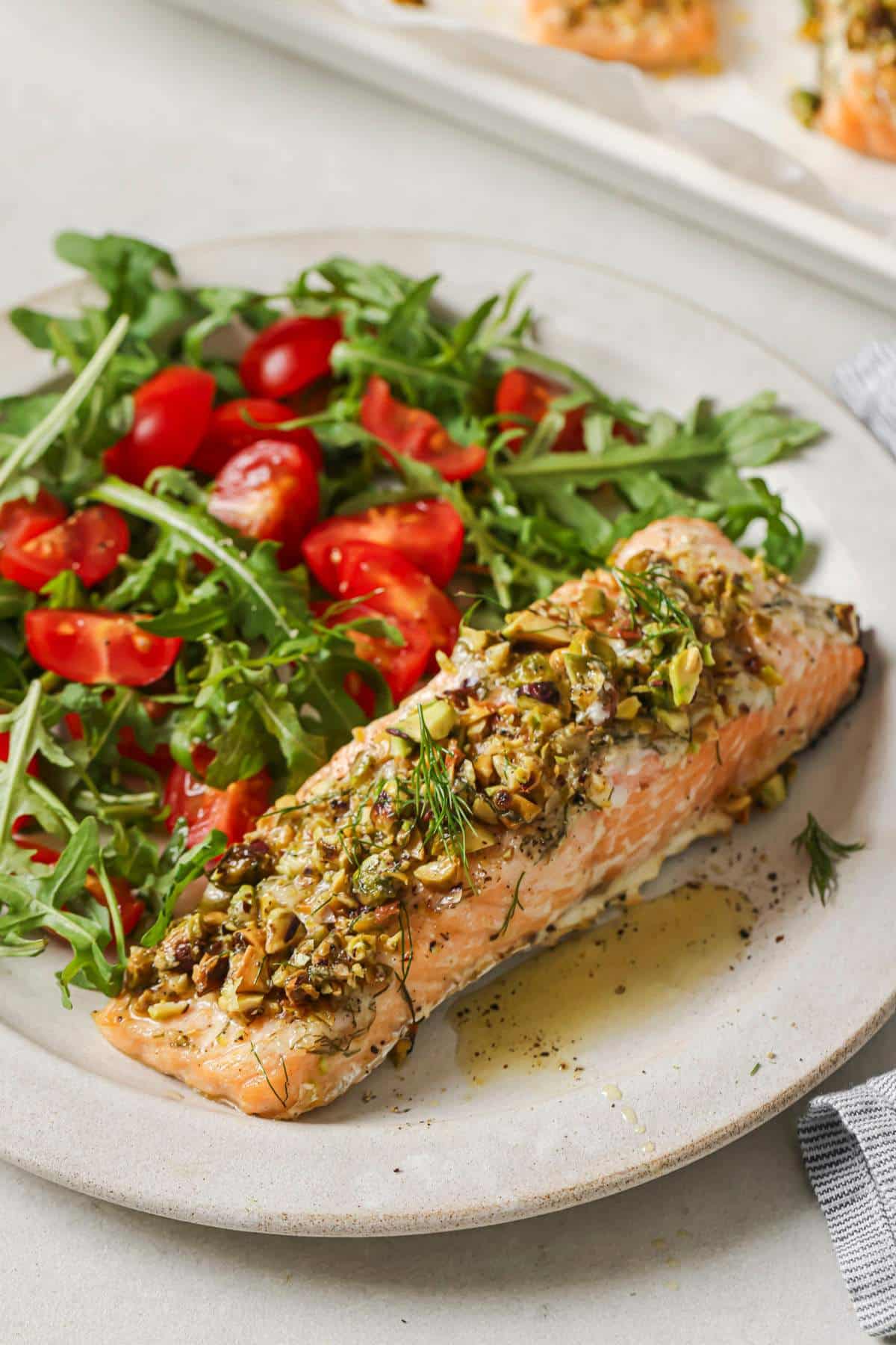 Pistachio crusted salmon served alongside a green salad with tomatoes.