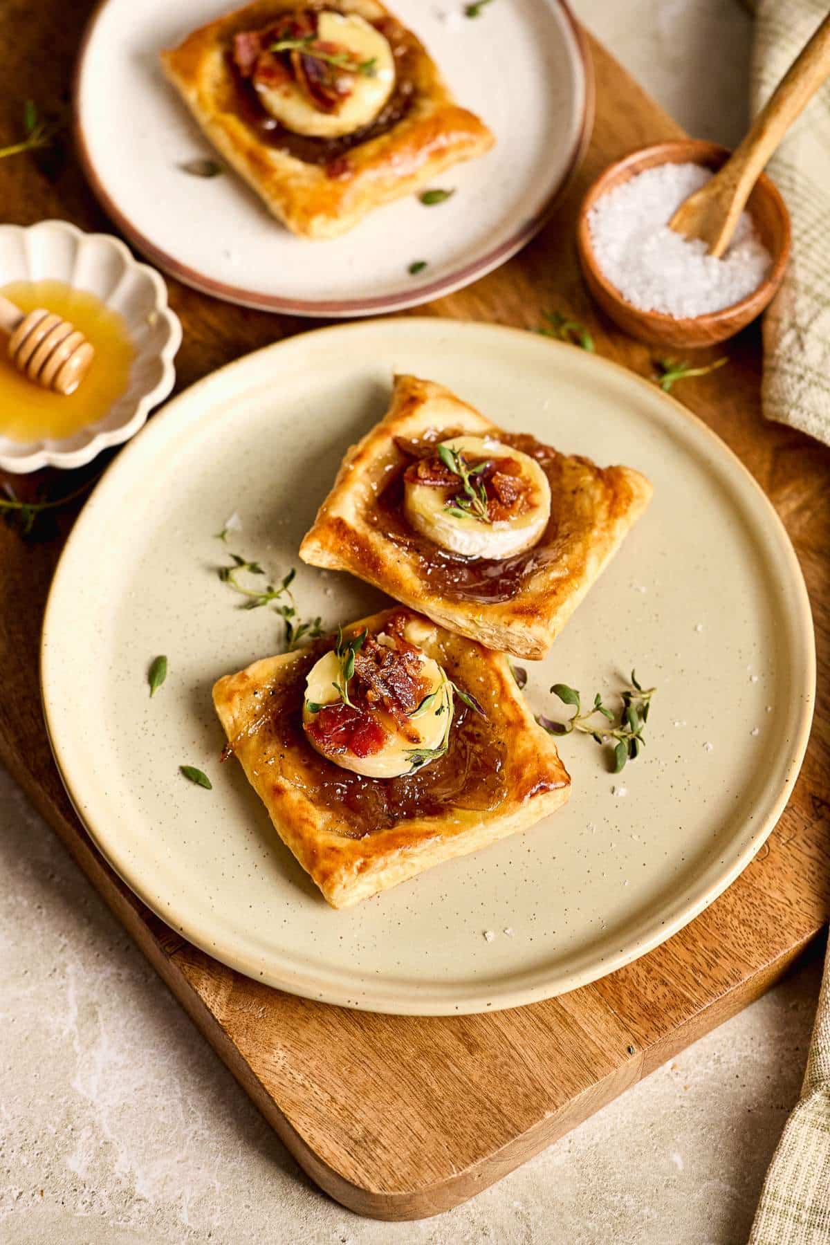 Puff pastry Brie Bites served on a plate with fresh thyme.