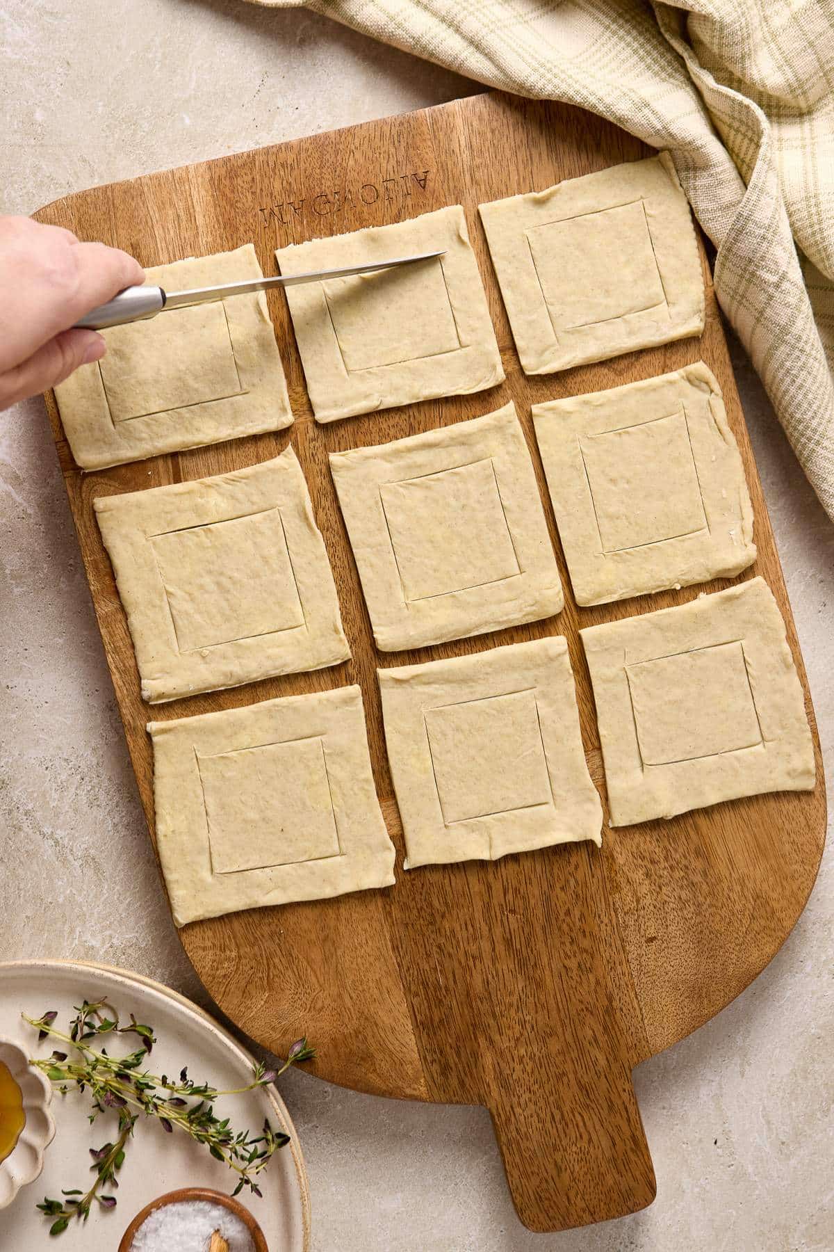 Using a knife to trace squares on puff pastry dough.
