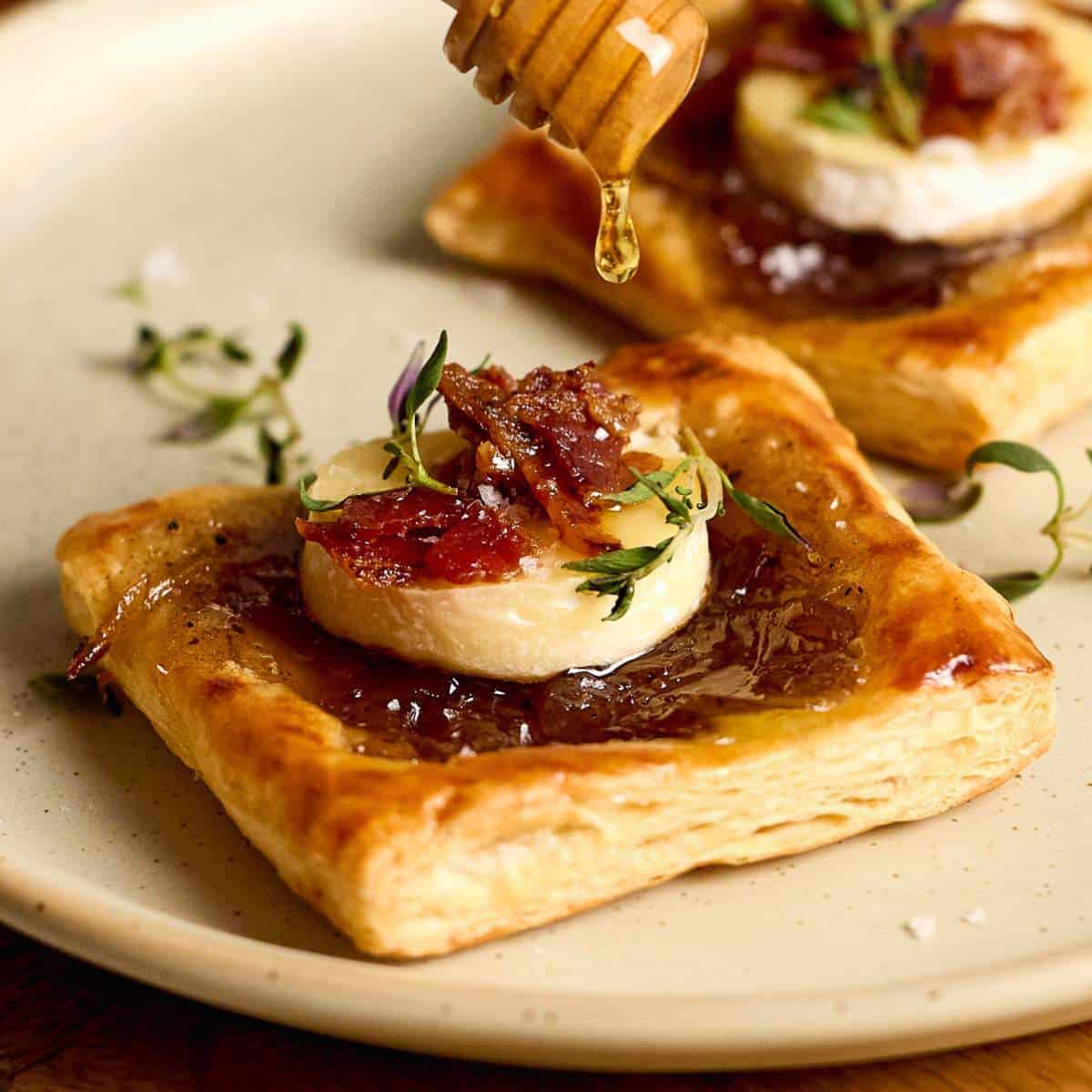 Drizzling honey over puff pastry brie bites.