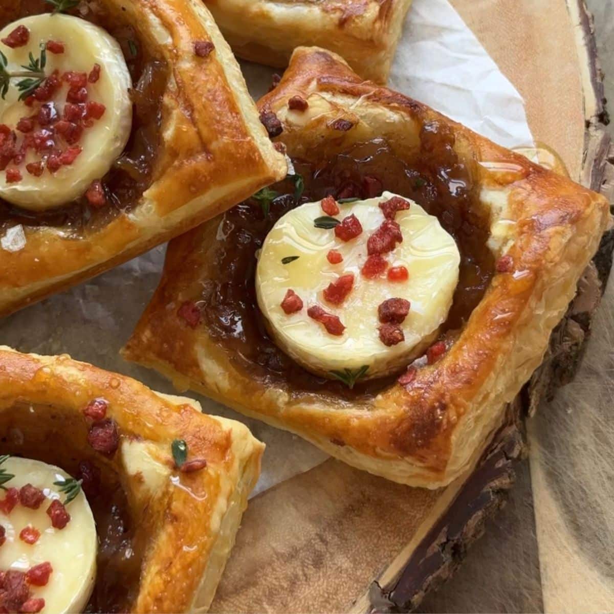 Puff pastry onion tarts on a serving display board.