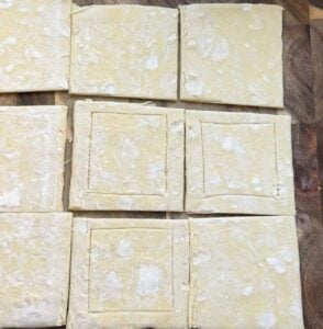 Puff pastry squares on a baking sheet pan.