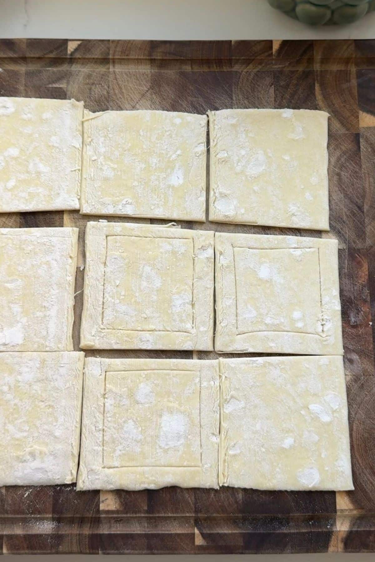 Puff pastry squares on a baking sheet pan.