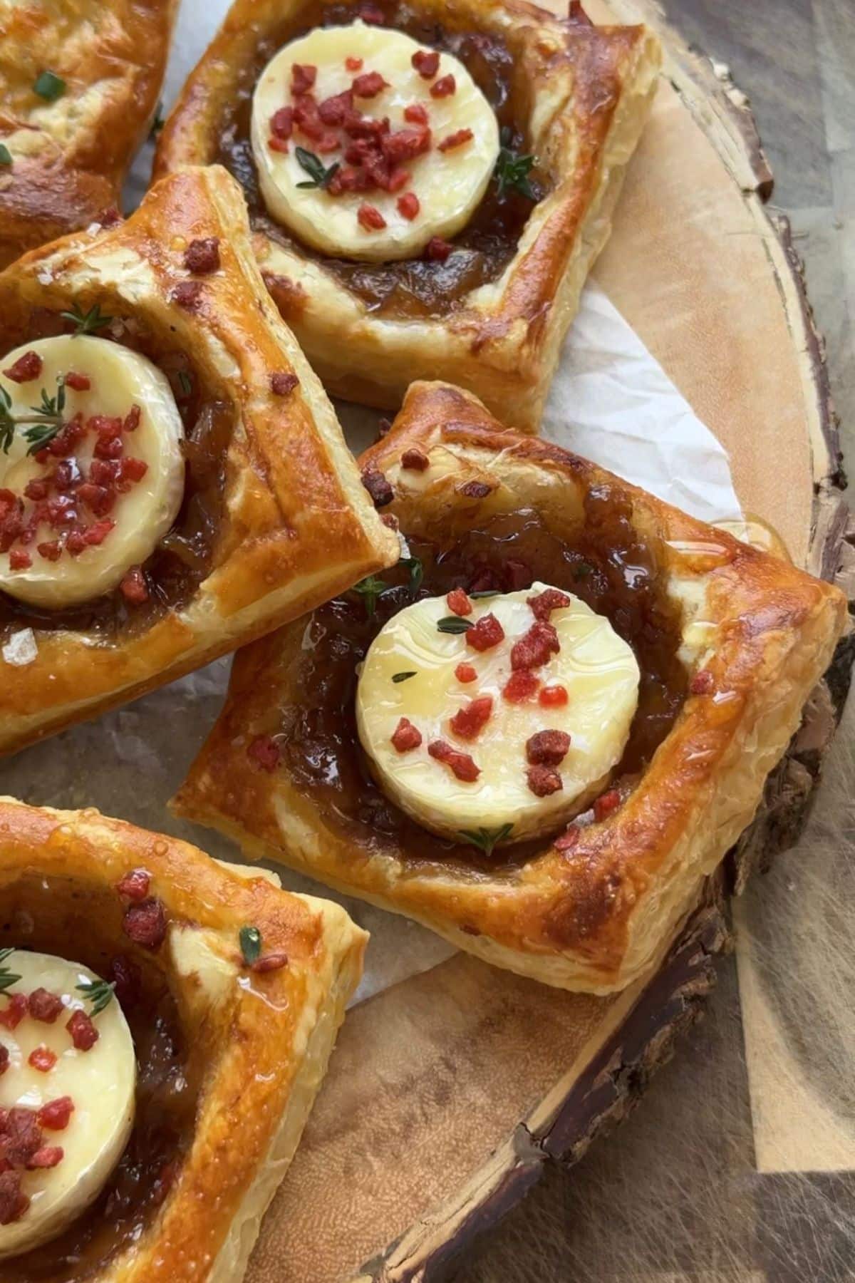 Puff pastry onion tarts on a serving display board.