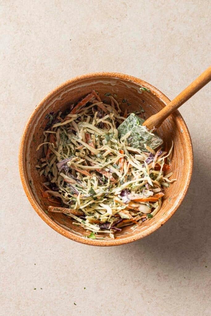 Using a rubber spatula to toss dressing with slaw.