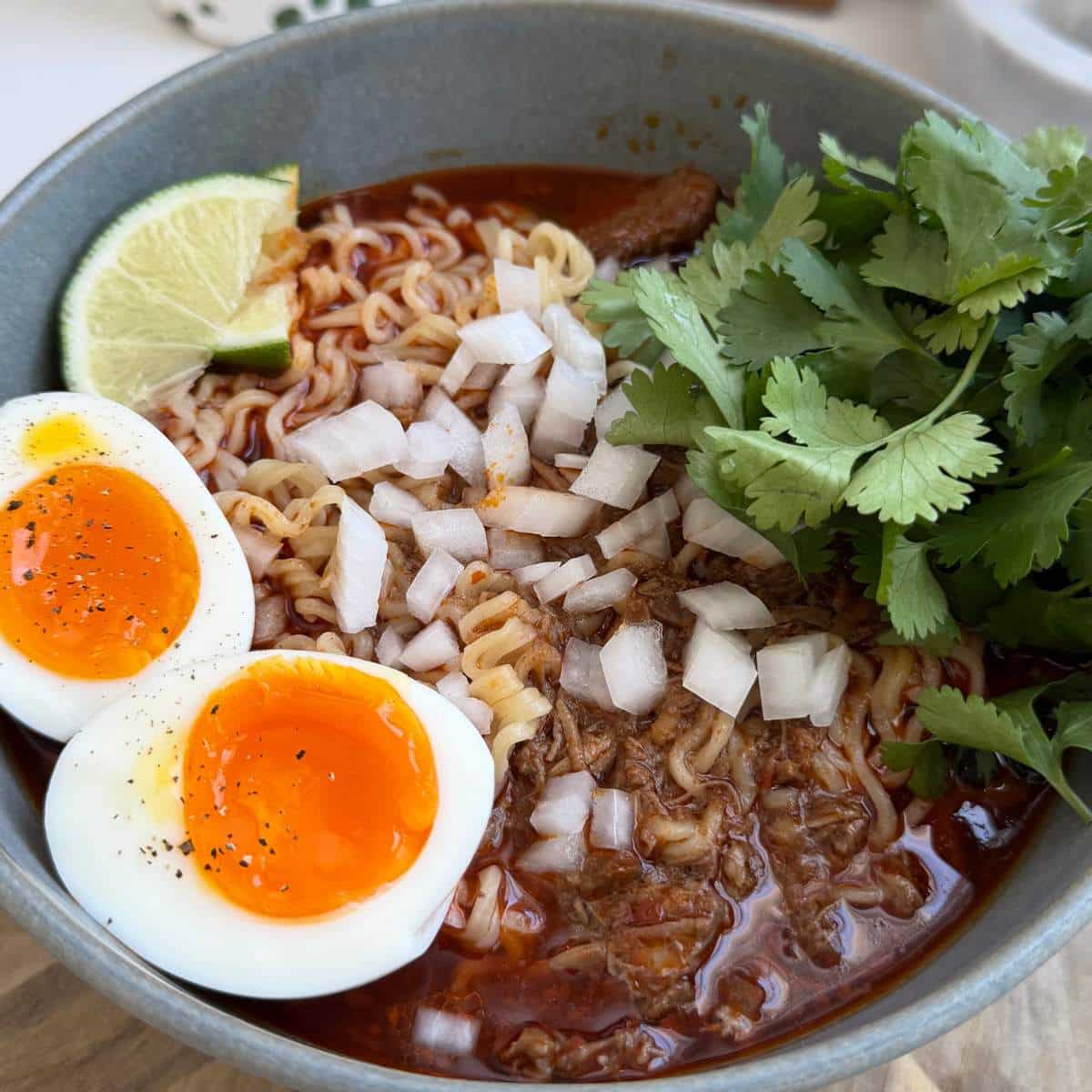 Birria Ramen served with a soft boiled egg, chopped onion and fresh cilantro.