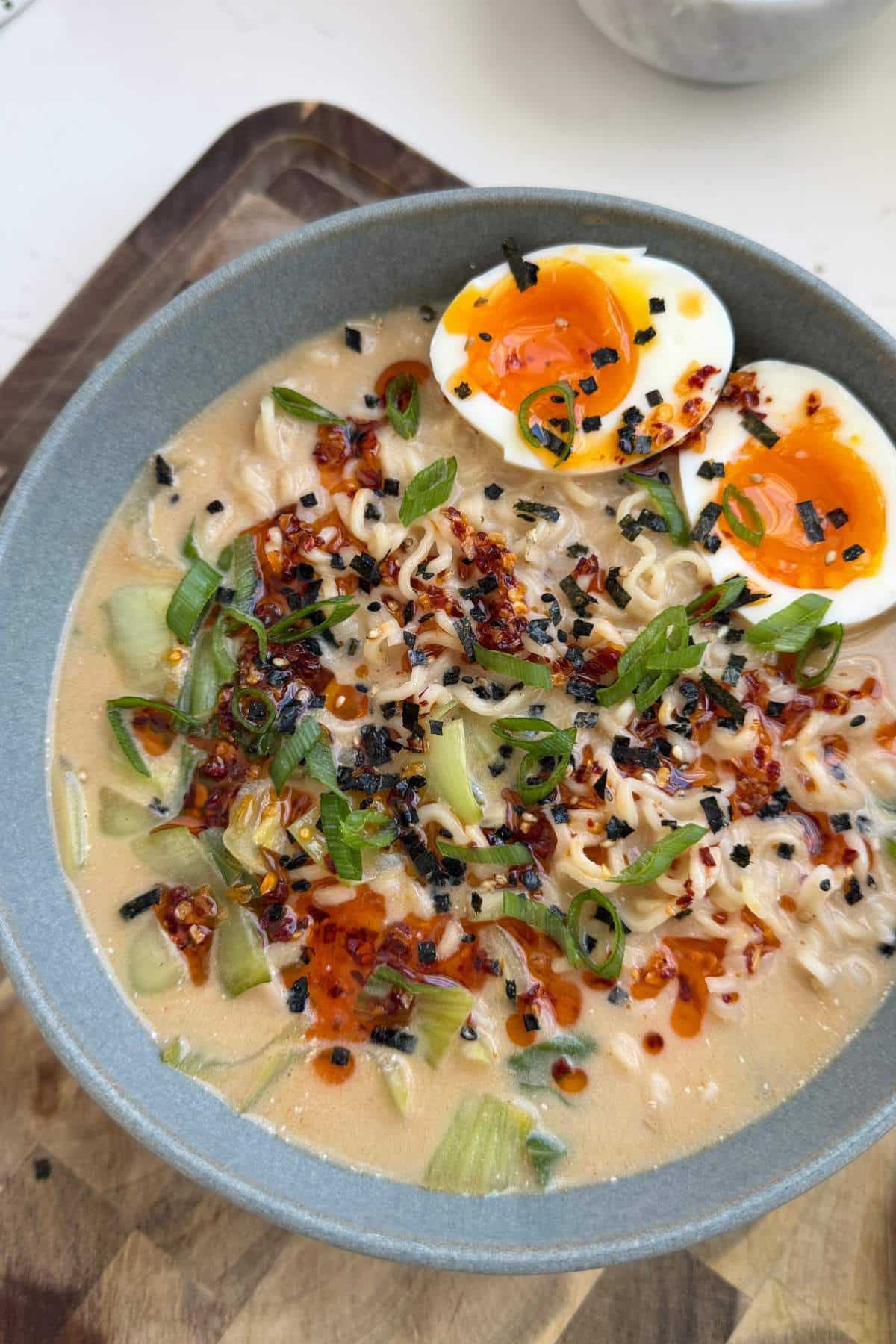 Spicy ramen topped with soft-boiled egg in a blue bowl.