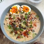 Spicy ramen topped with soft-boiled egg in a blue bowl.