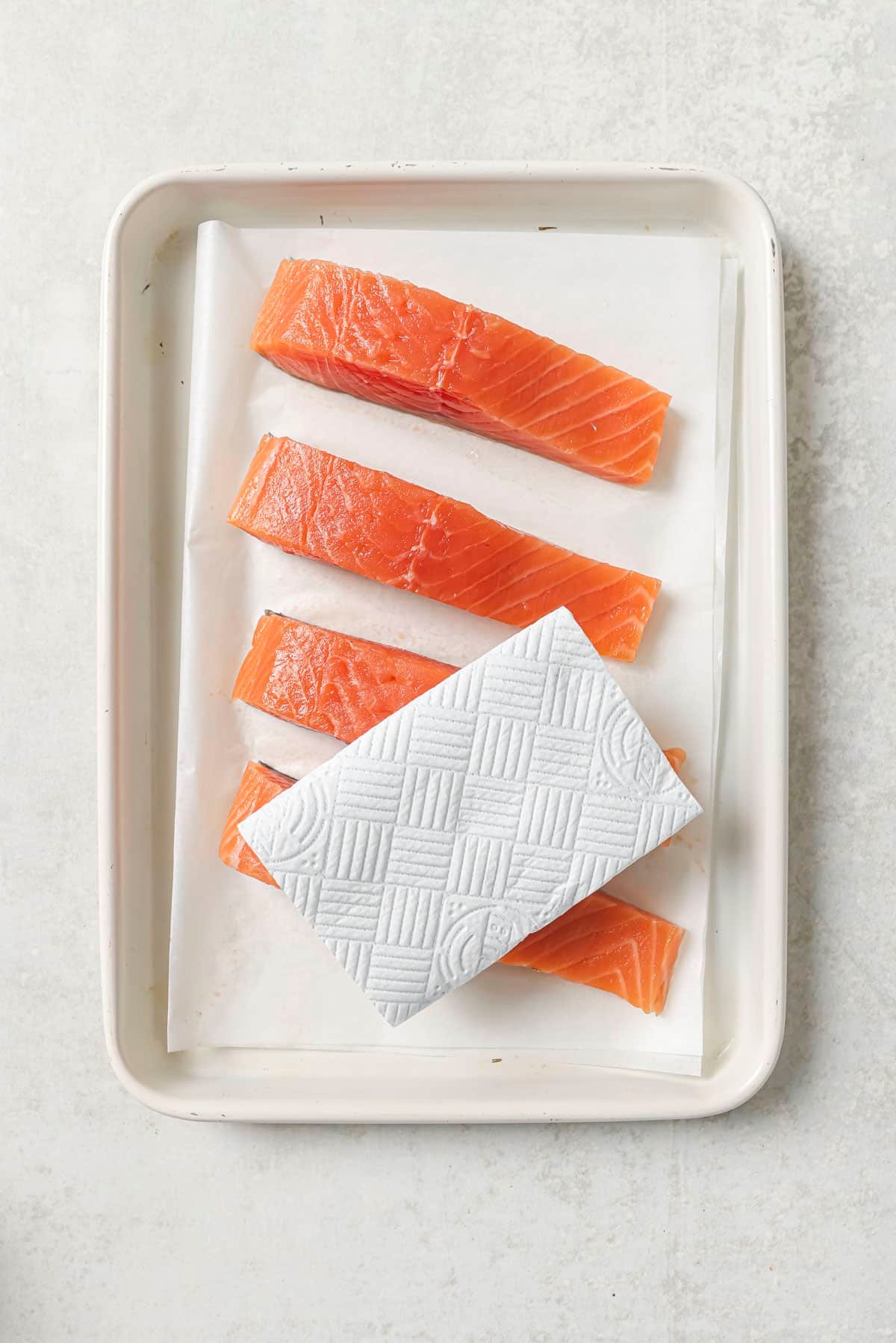 Patting salmon fillets dry with a paper towel.
