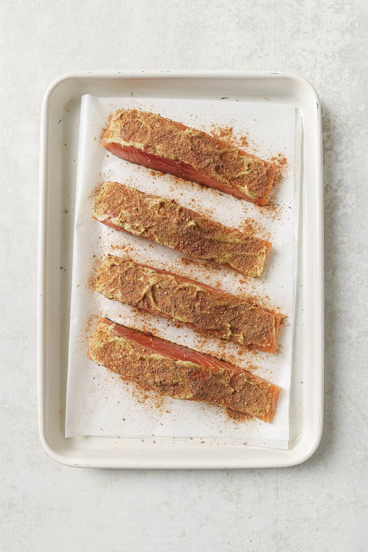 Seasoned salmon on a baking tray.