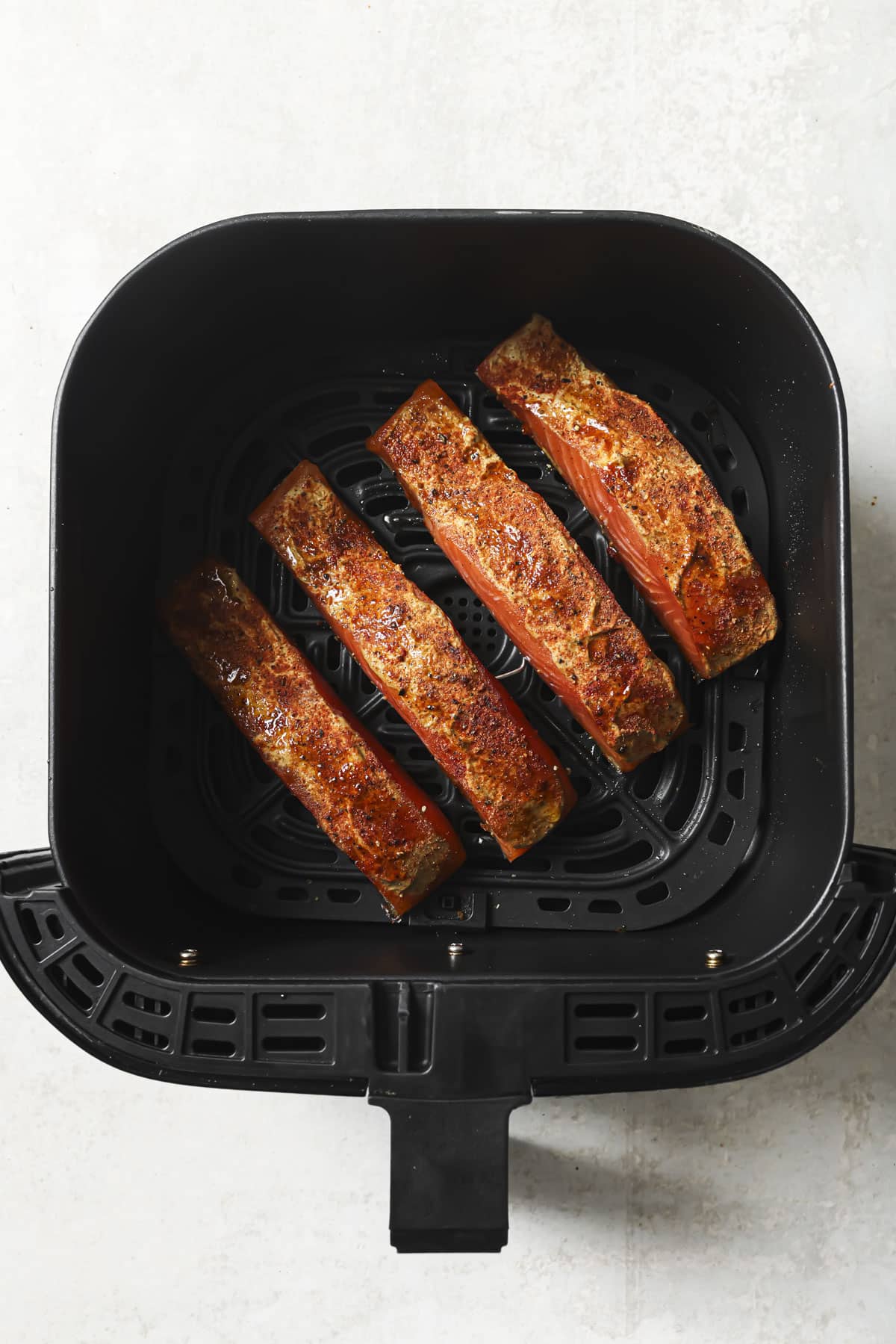 Cooked salmon in an air fryer basket.