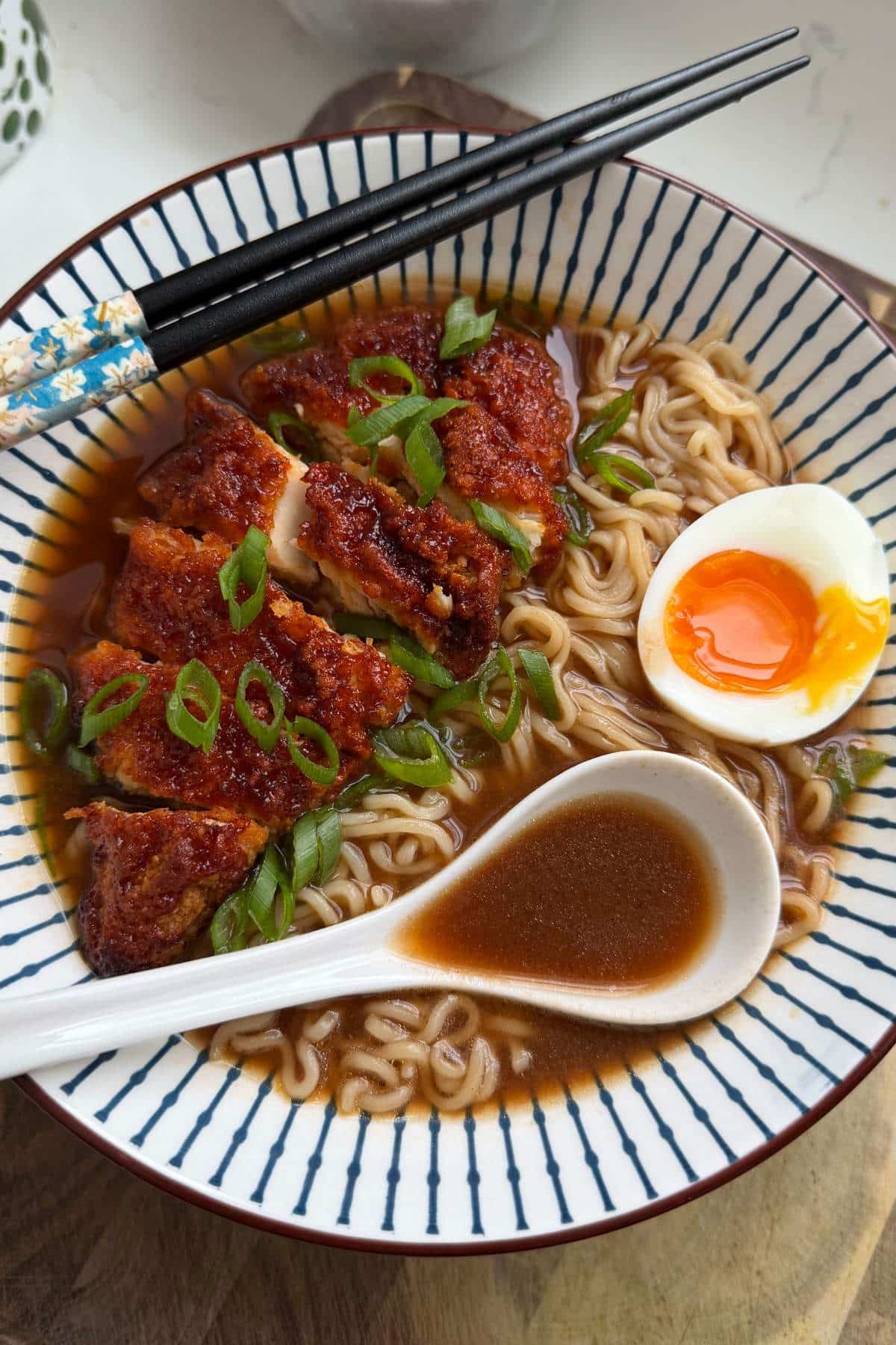 Gochujang Honey Chicken Ramen served in a bowl with a soft-boiled egg and chopsticks.