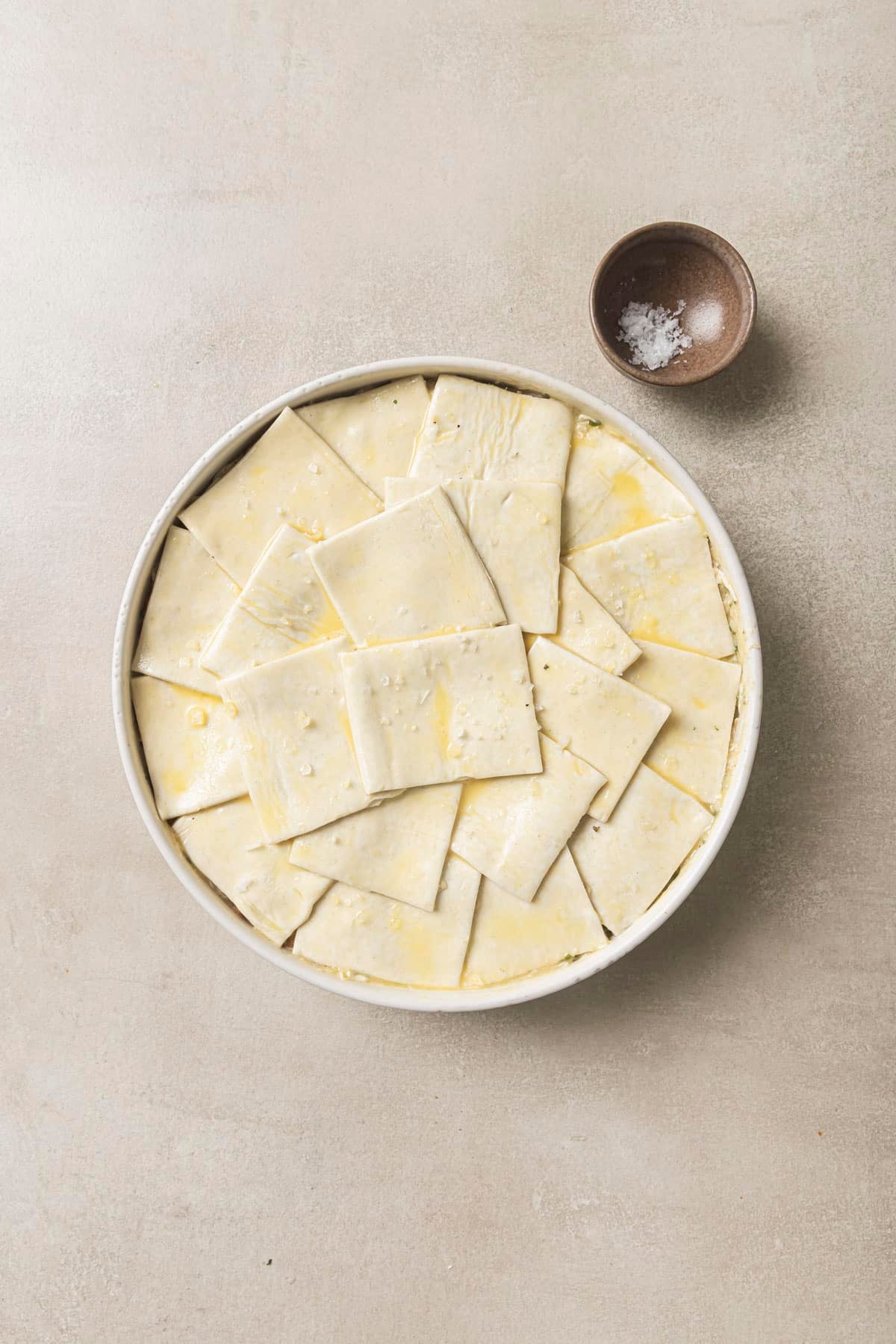 Pieces of puff pastry dough layered over pot pie mixture.
