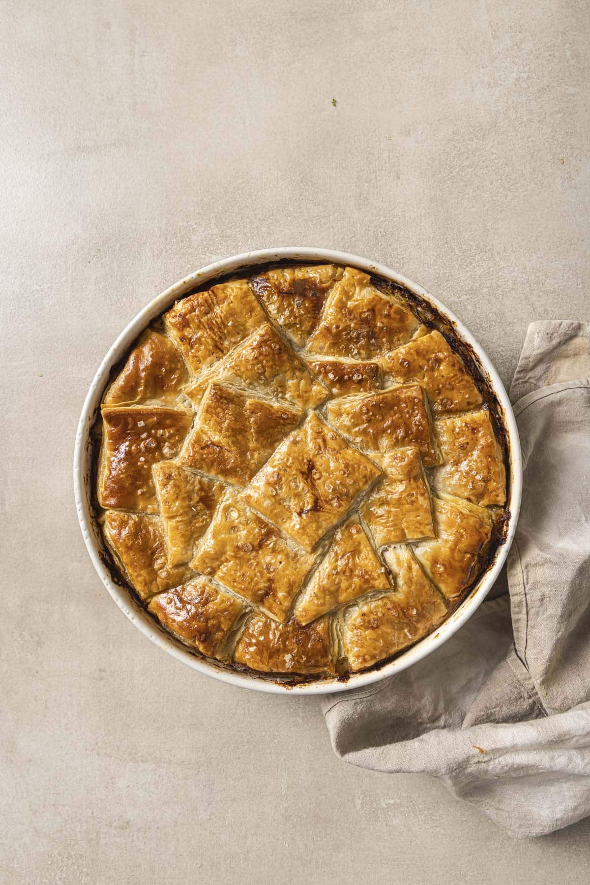 Baked puff pastry pot pie in a white baking dish.