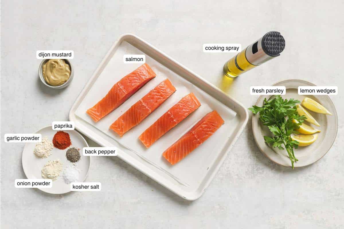 Seasonings on a plate next to uncooked salmon fillets and fresh parsley.