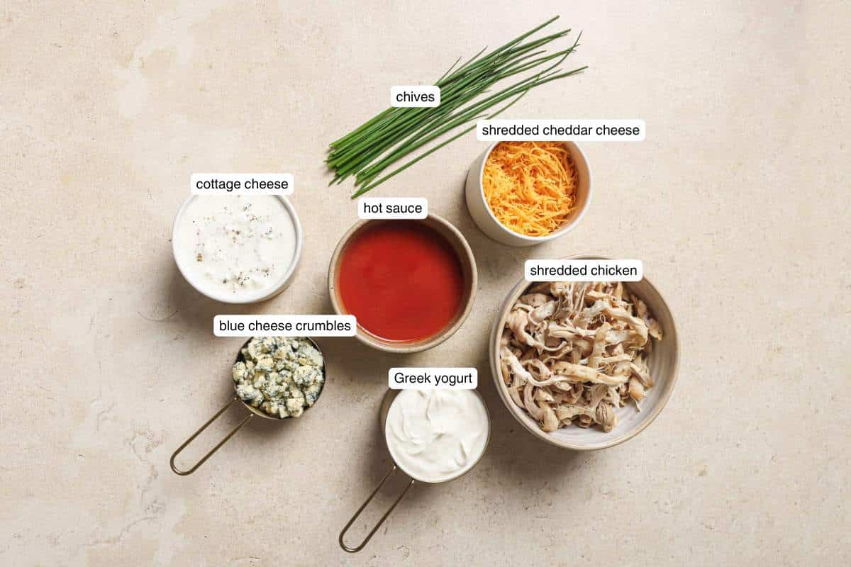 Small bowls with shredded cheese, shredded chicken, hot sauce, cottage cheese and Greek yogurt.