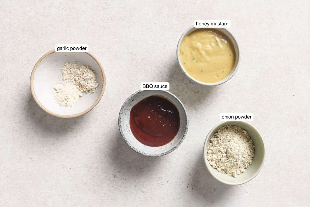 Small bowls filled with honey mustard, BBQ sauce and seasonings.