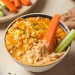 Healthy buffalo chicken dip served in a small bowl with a carrot and celery stick.