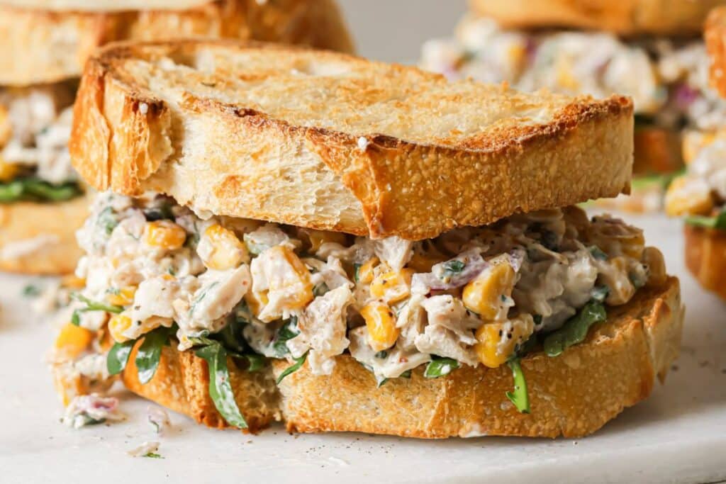 street corn chicken salad served between 2 slices of toasted sourdough bread. 
