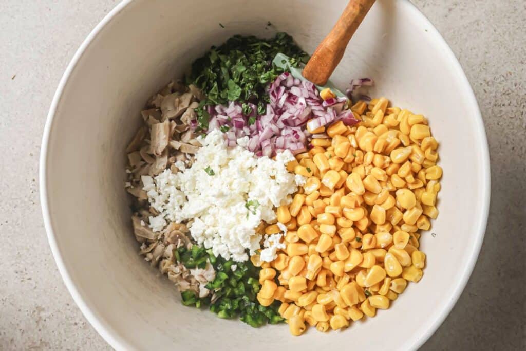 all of the ingredients for mexican street corn chicken salad in a mixing bowl before the dressing is added. 