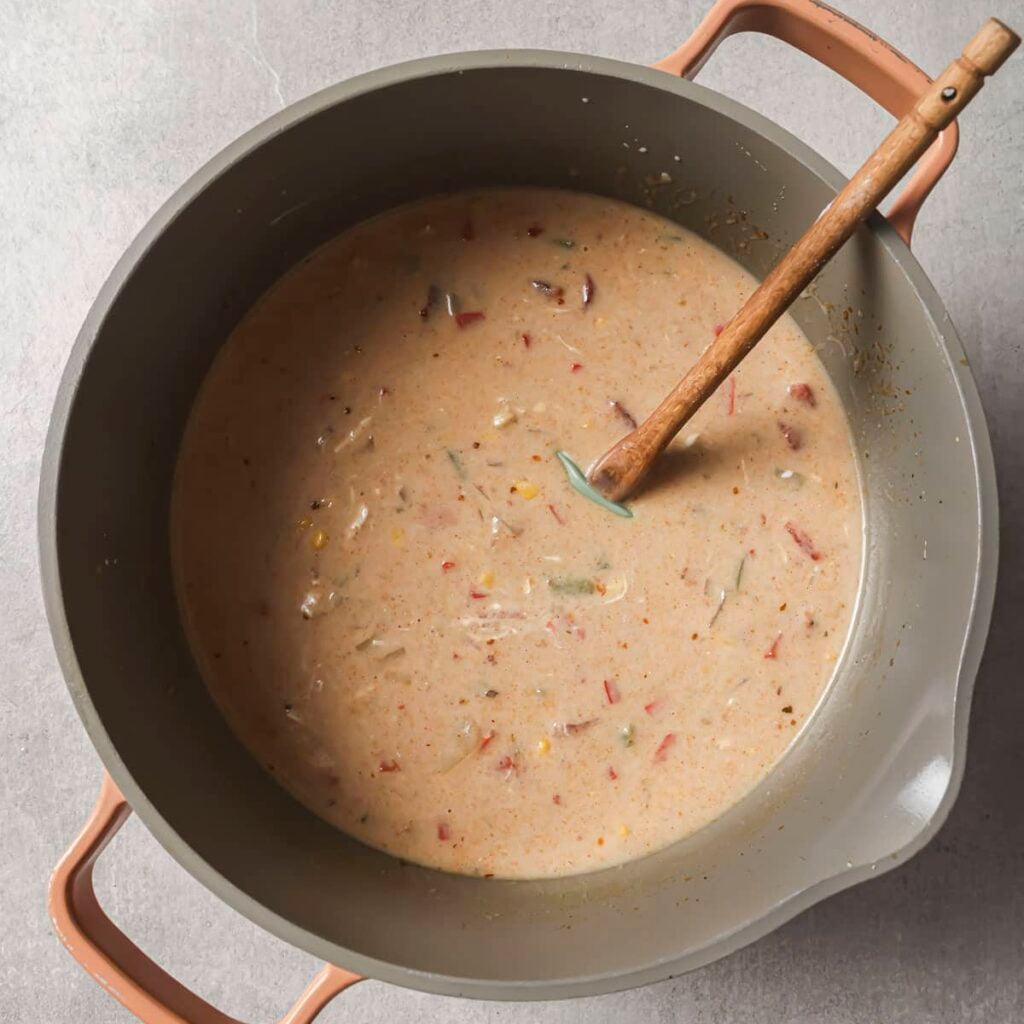 a pot of creamy chicken fajita soup with a wooden spoon resting on the side