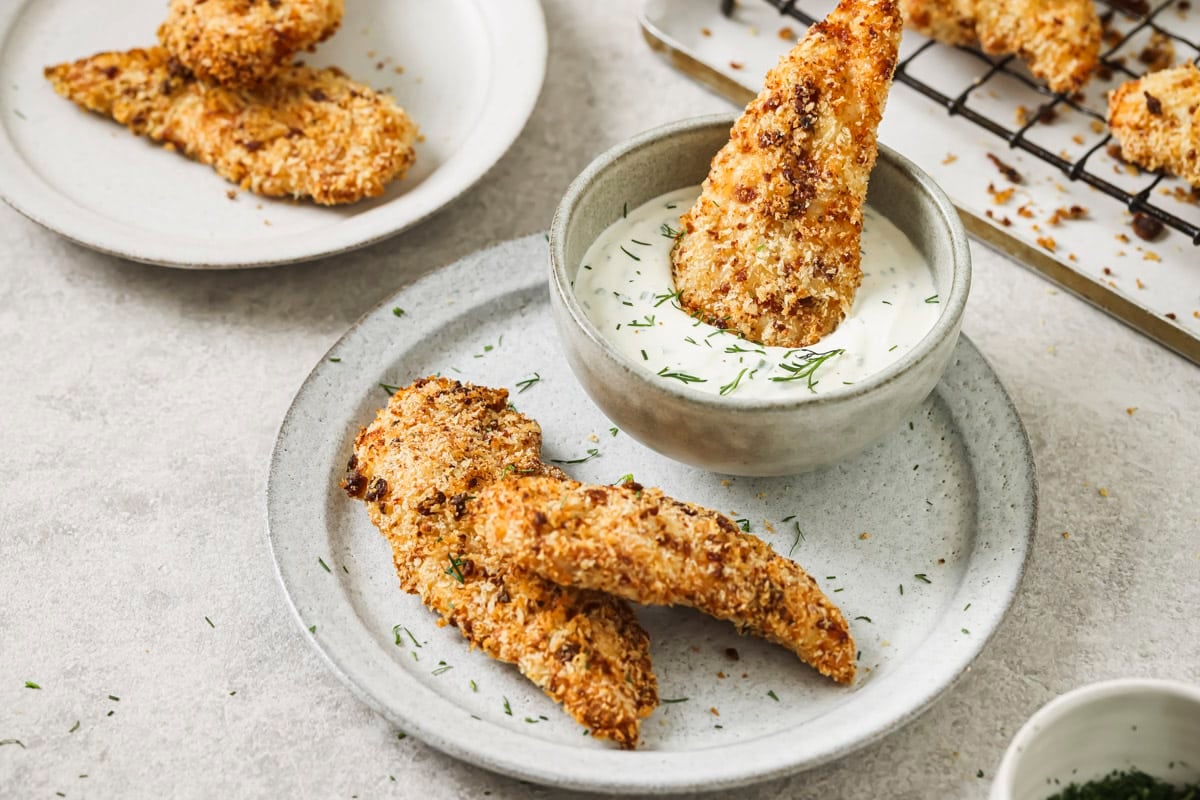 dipping a bacon ranch chicken tender into a bowl of ranch dressing