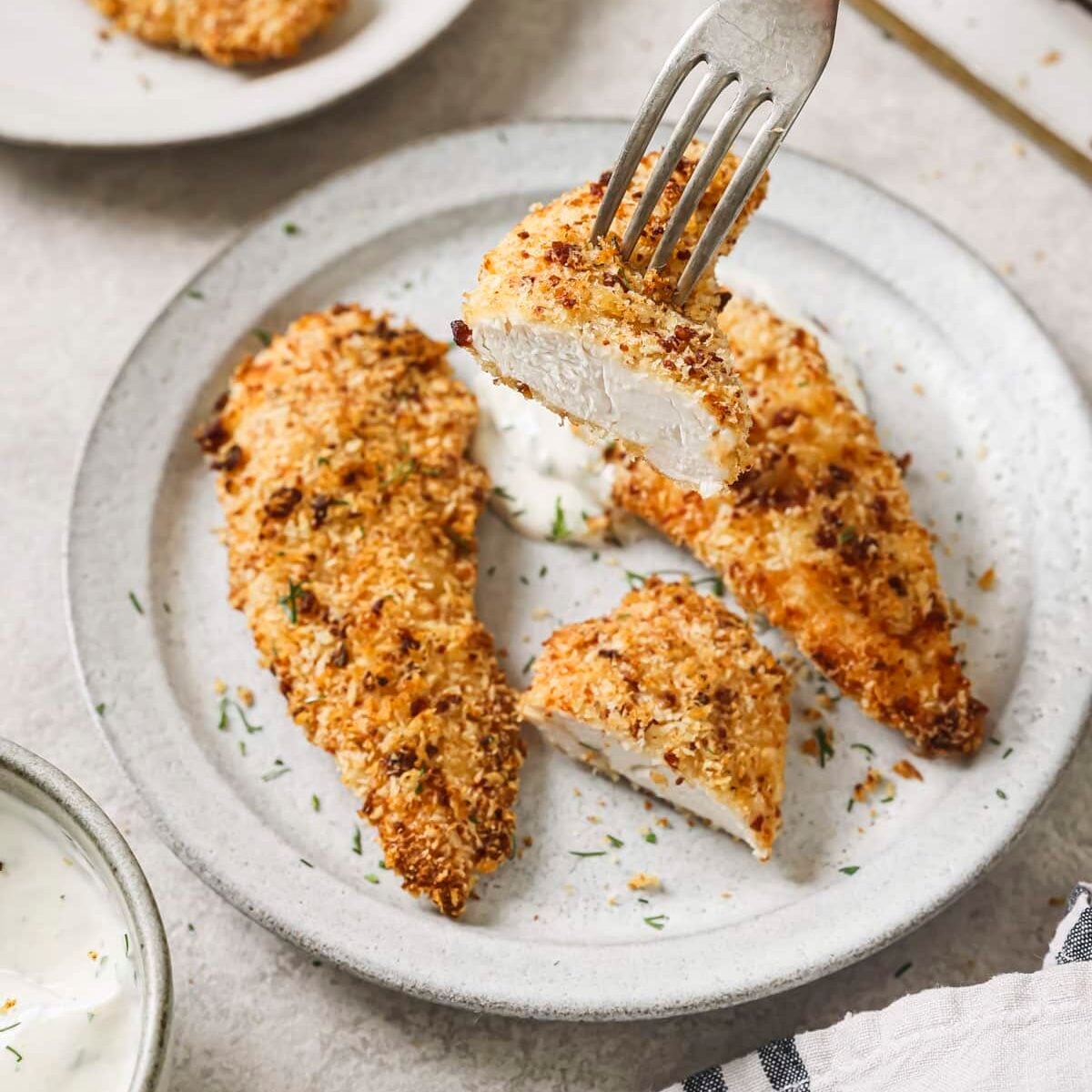 Crispy bacon ranch chicken cut on a plate with a fork lifting a piece up.