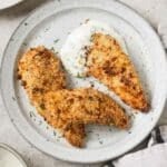 three crispy bacon ranch chicken tenders on a white plate with a dollop of ranch dressing