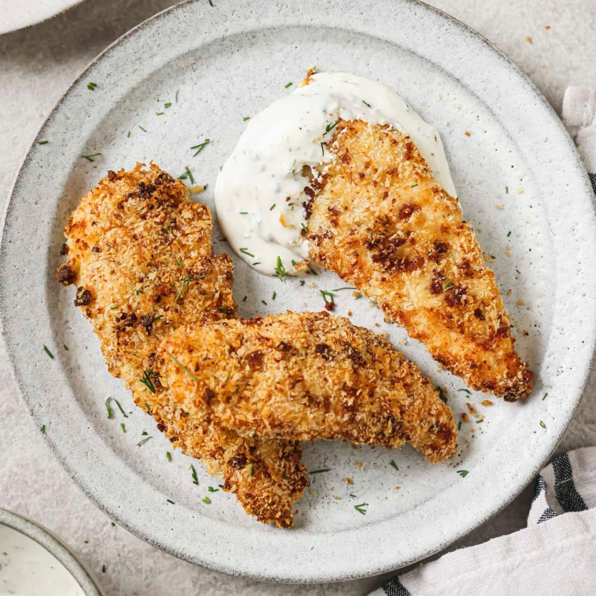 crispy bacon ranch chicken on a white plate with ranch dressing
