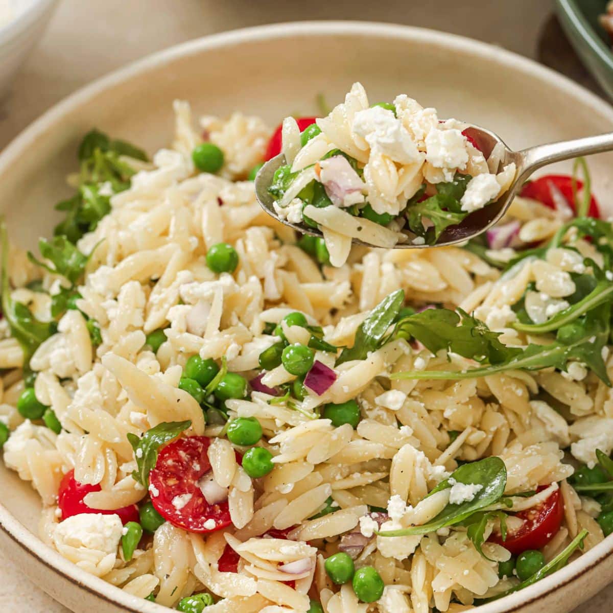 A fork lifting a spoonful of lemon orzo pasta salad. 