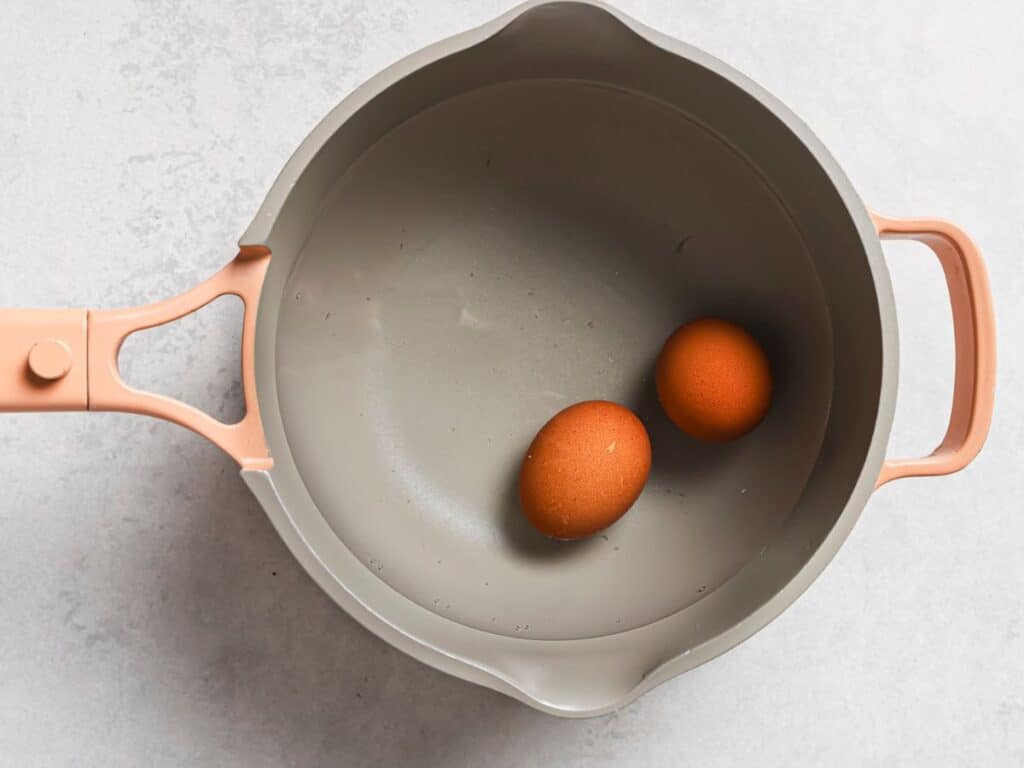 two eggs in a saucepan boiling to make them jammy in the middle