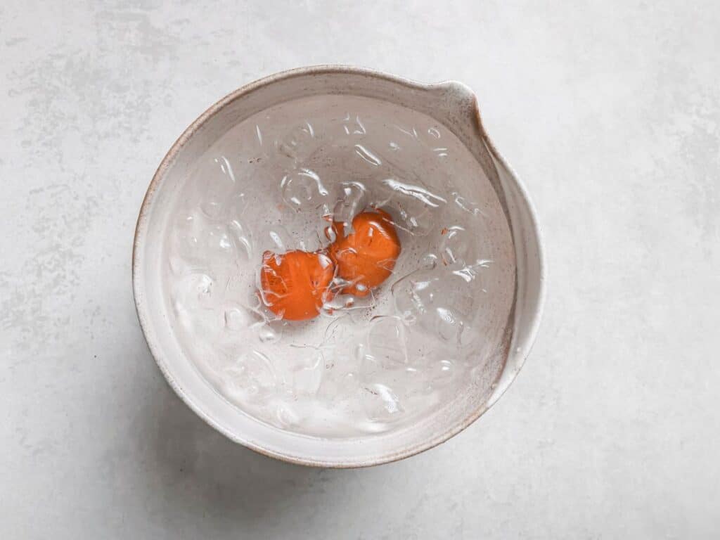 two eggs in an ice bath to stop the cooking process
