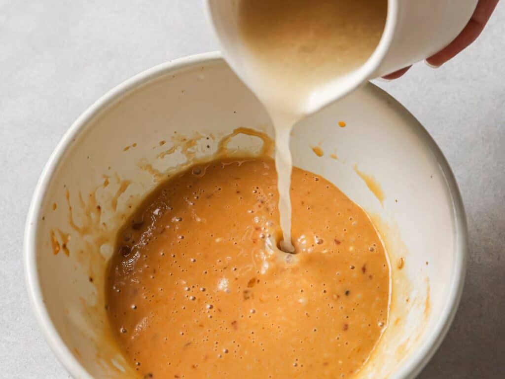 pouring the egg mixture into the spicy ramen sauce